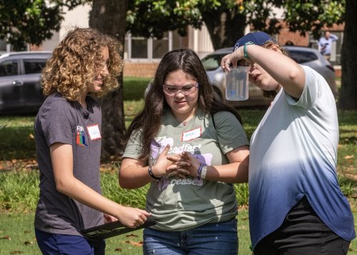 Three students looking at a glass of water