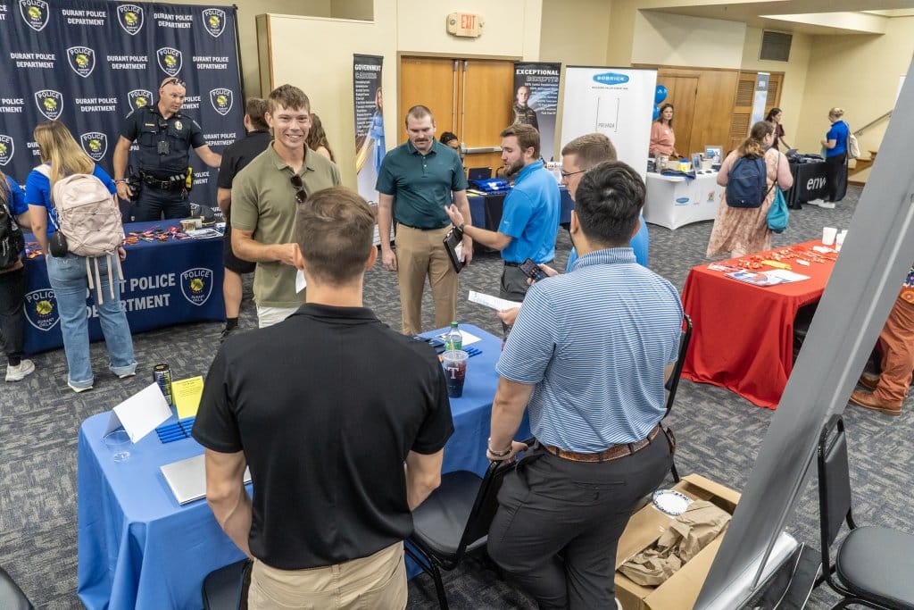 A group of Southeastern students speaking with a potential employer at a table at a career fair