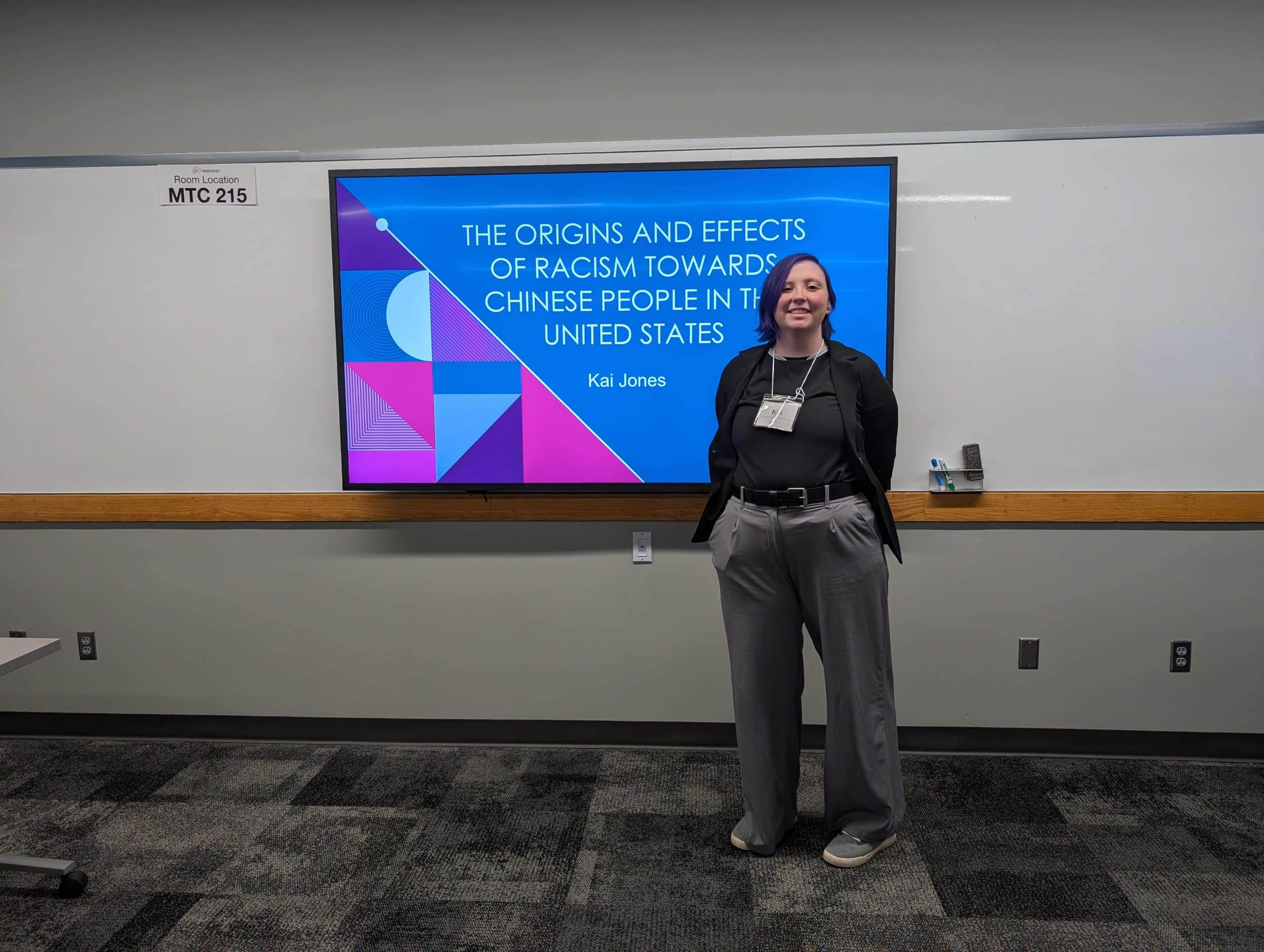A woman standing in front of a monitor in a classroom