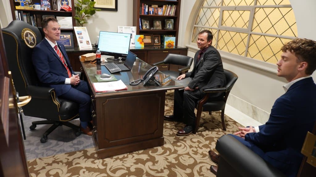 Three men in suits having a meeting in a professional office setting.