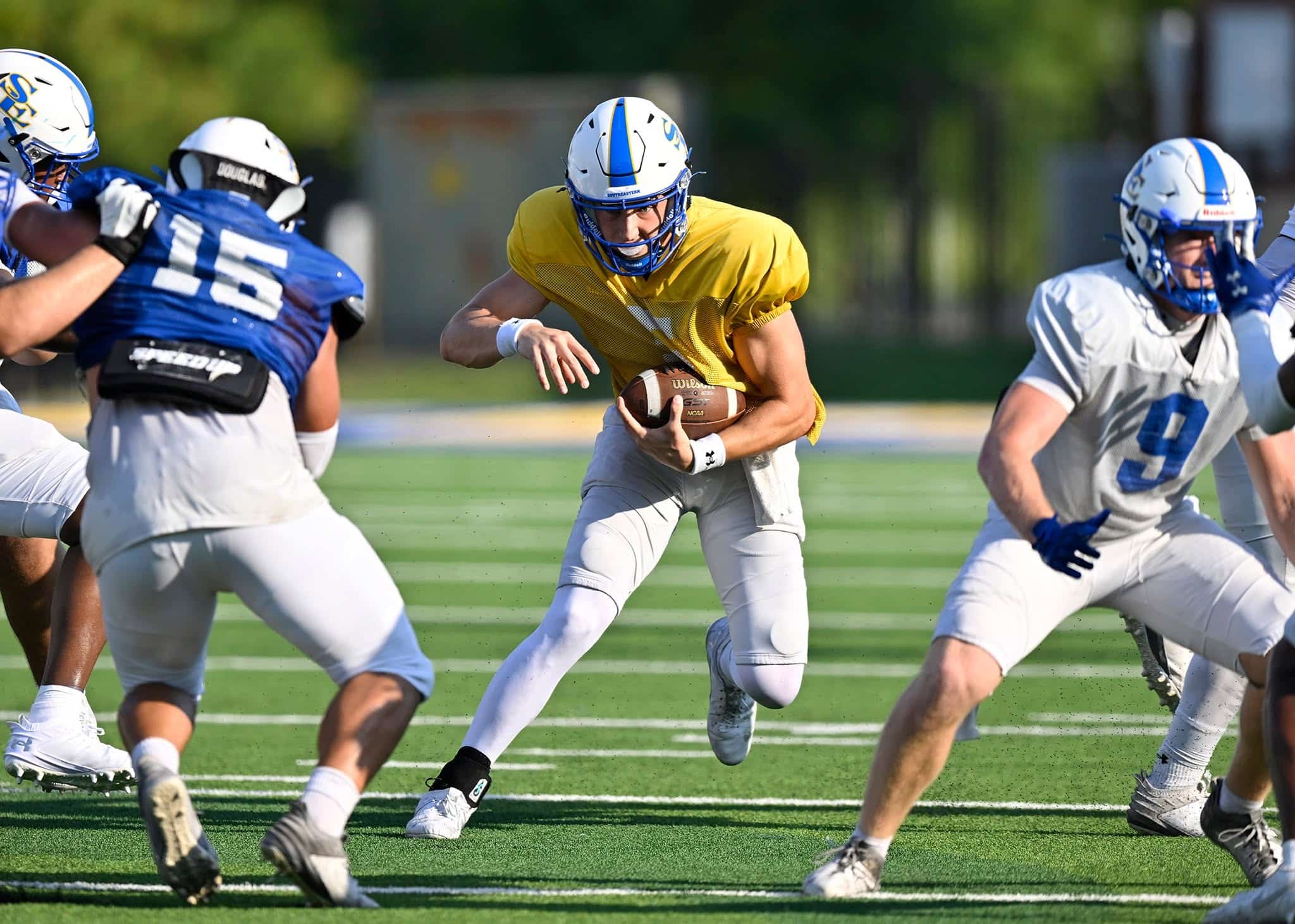 A Southeastern football player carries the ball during a scrimmage.