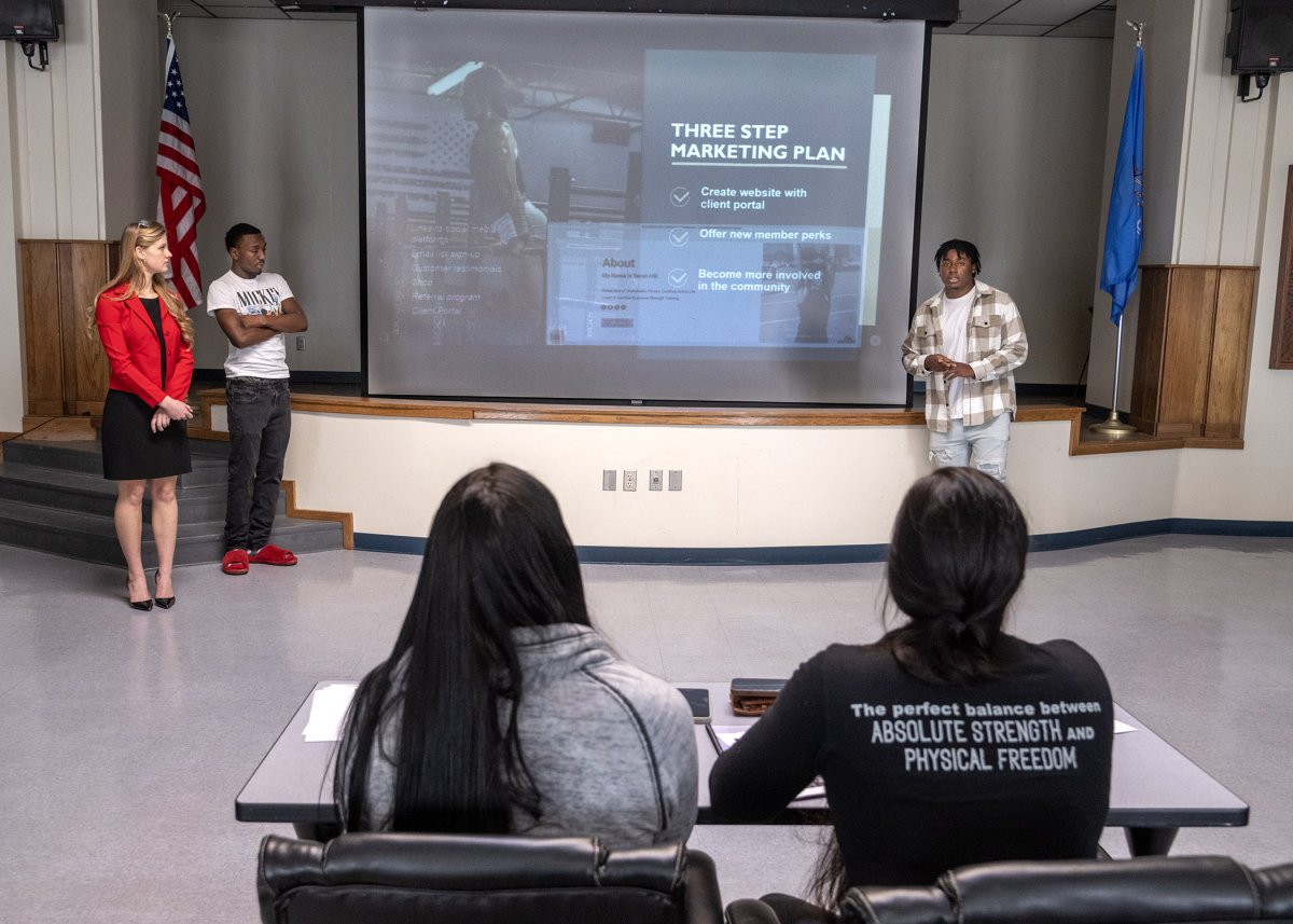 Principles of Marketing students present real-world applications and plans to local business owner banner